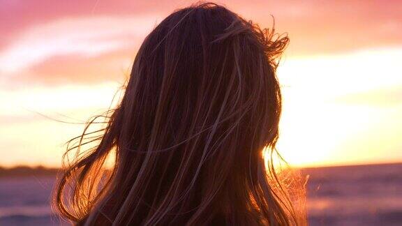 特写:年轻的女摄影师看着美丽的夕阳和大海
