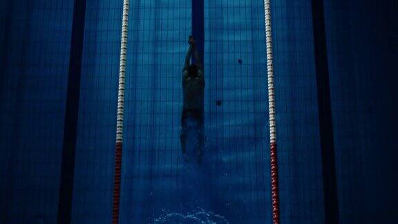 鸟瞰图男性游泳运动员跳跃潜入游泳池职业运动员赢得世界冠军黑暗戏剧性的饱和颜色电影的光艺术的上下天桥慢动作