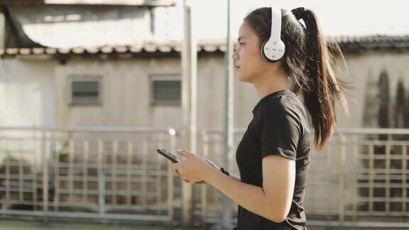 快乐的女运动员戴着耳机用智能手机听着音乐在城市里跑步慢跑的生活方式健康