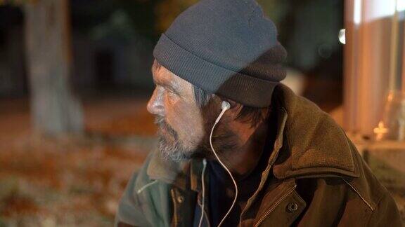 晚上戴着耳机在街上孤独寒冷的流浪汉的脸