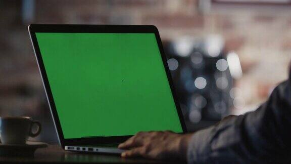 一名男子在咖啡馆使用绿屏笔记本电脑