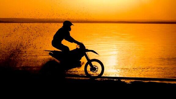 越野摩托车极端转弯河边日落时骑摩托车的人极限越野摩托车车轮下有泥土