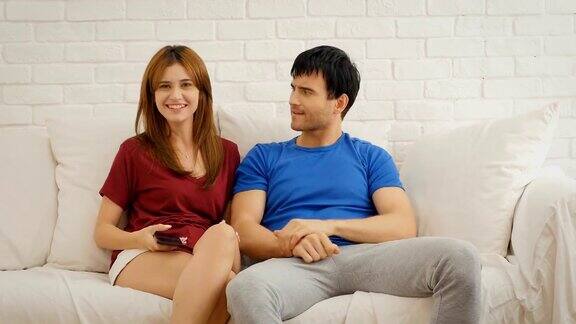 一对年轻夫妇在起居室看电视为了抢遥控器而吵架