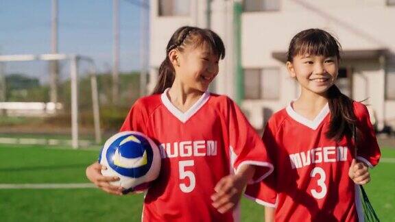 两名女足或足球队队员抱着足球边走边聊