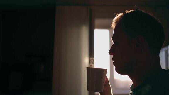 一个人的剪影与一杯热咖啡在日出的背景