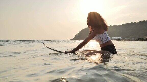 美丽的年轻女子坐在冲浪板上等待海浪体育cinemagraph