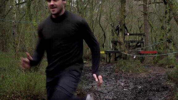 男人在泥泞中奔跑穿过林地-慢镜头