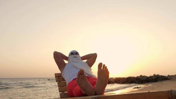 有趣的圣诞老人晒日光浴圣诞老人戴着太阳镜躺在海边的沙滩上休息圣诞老人在海边度假