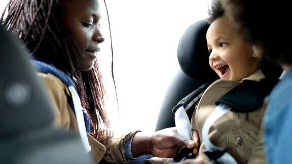 母亲把女儿固定在汽车座椅上