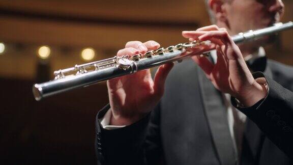 笛子手在交响乐团或铜管乐队演奏笛子特写在男性手中