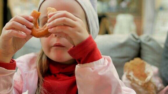 小女孩在咖啡馆吃着美味的甜甜圈