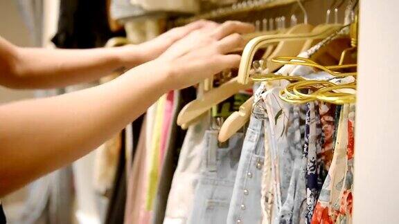 一位女士在一家服装零售店挑选一件衣服近距离的手