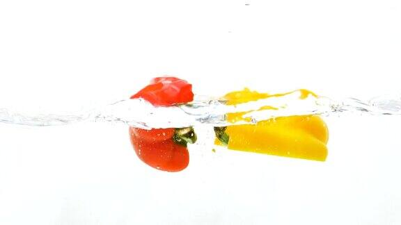 红、黄柿子椒滴入水中的慢动作