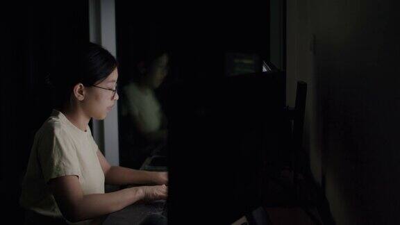 亚裔自由职业妇女戴着眼镜在电脑上敲击键盘搜索资料