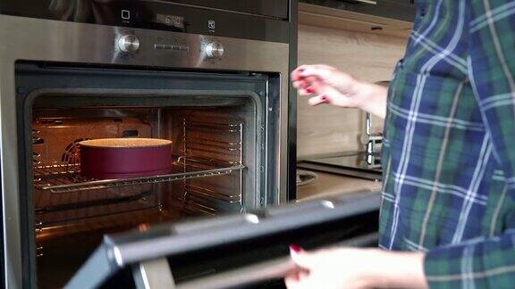女人把蛋糕放进烤箱并设置烤箱温度