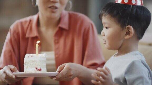 亚洲生日男孩吹蛋糕上的蜡烛