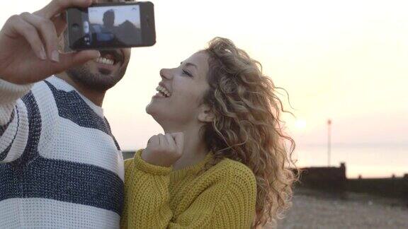 一对夫妇在海滩上用手机相机自拍