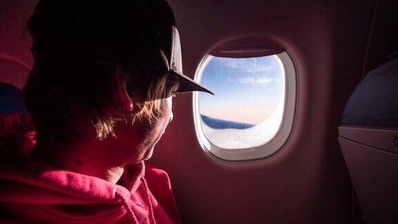 年轻男性乘客在飞行中透过飞机窗户看