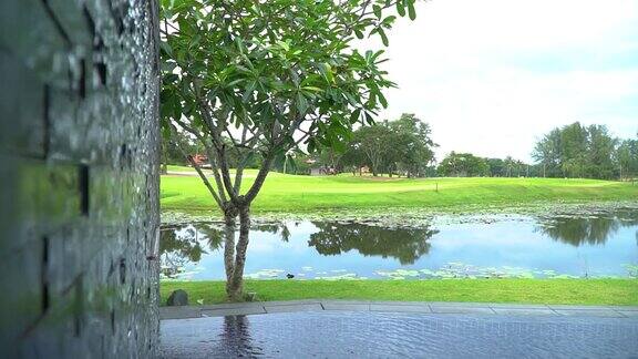水池中的墙瀑布可以看到池塘和绿色的高尔夫球场
