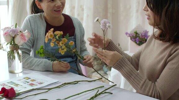 年轻的花商正在训练她的朋友如何做花束