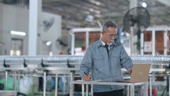 华籍工作高级领班使用笔记本电脑在制造工厂制定生产计划