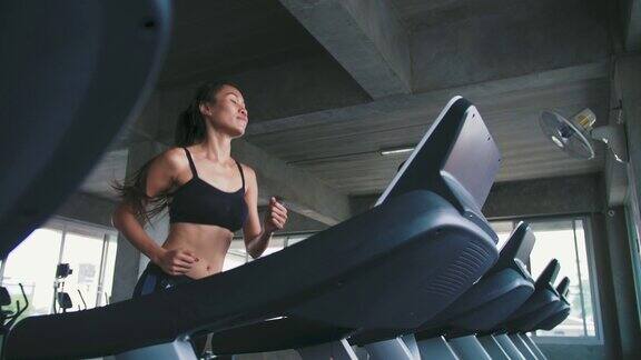 一个女人在健身房跑步机上锻炼