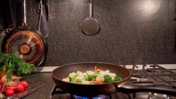 在煤气炉上的煎锅里煎这些蔬菜混合物