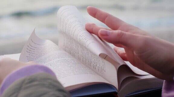 风以慢动作翻动书页打开的书躺在海边的长椅上4k60p