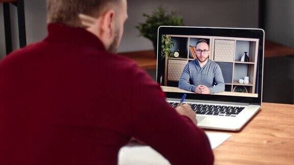 商业男性与同事聊天在线视频电话远程会议使用笔记本电脑在家里工作