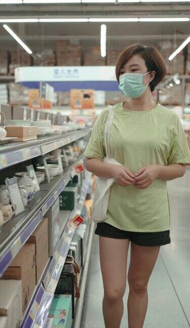 一位女士带着一次性医用口罩在超市购物