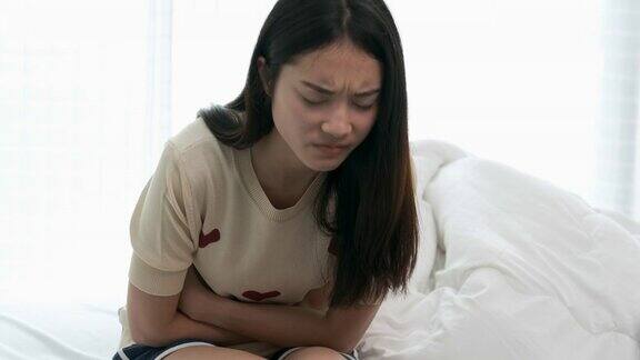 亚洲女性早上在卧室床上醒来时会胃痛