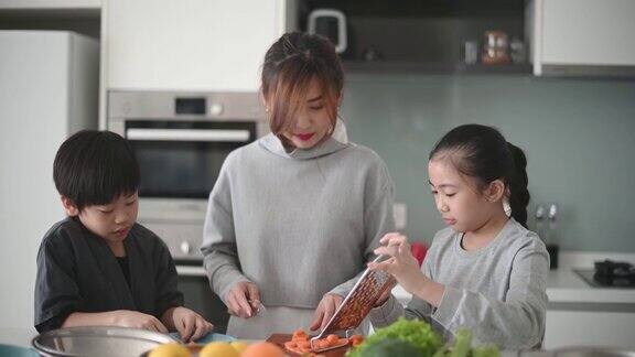母亲和女儿儿子在厨房里切胡萝卜