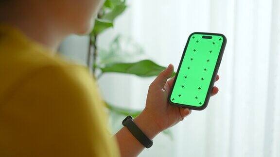 女士拿着智能手机在客厅用绿色屏幕滚动