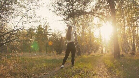 迷人的年轻女子穿着毛衣牛仔裤在花苹果树跳舞和纺纱夕阳春天的果园和绿色的田野缓慢的运动