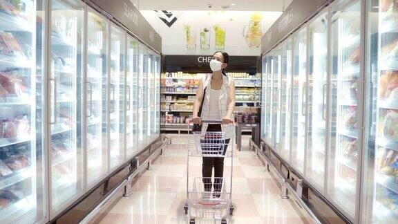 年轻的亚洲妇女在超市购物并戴上面罩以保护健康防止灰尘和病毒