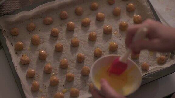 厨房里亚洲华人中位成年妇女正用手在烤盘上的花生饼干上刷蛋黄