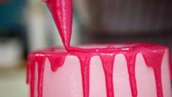 糖果厨师用糕点袋装饰手工制作的粉色奶油蛋糕用滴霜的浆果甘纳许特写