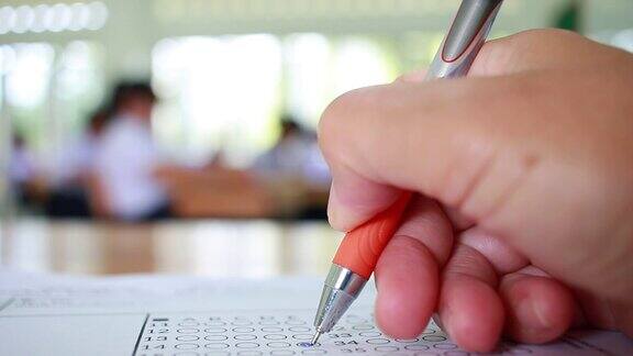 考试考试学校或大学概念:学生手持铅笔书写标准化答案的多重复写纸形式与灰黑色的答案表泡问题在考试评估