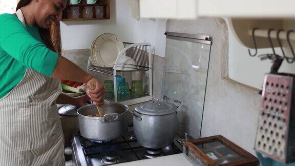 老女人在家里的老式厨房里煮鹰嘴豆汤-慢镜头