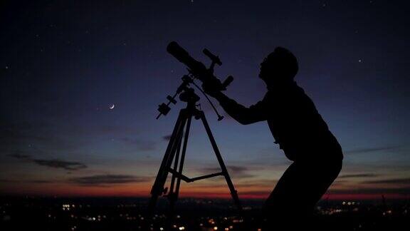 一个男人用天文望远镜观察星空的剪影