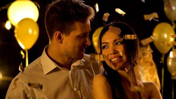 白人男人和美丽的亚洲女人在飘落的五彩纸屑下跳舞派对