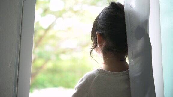 小女孩望着窗外挥手