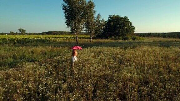 拿着红伞的女孩走在草地上