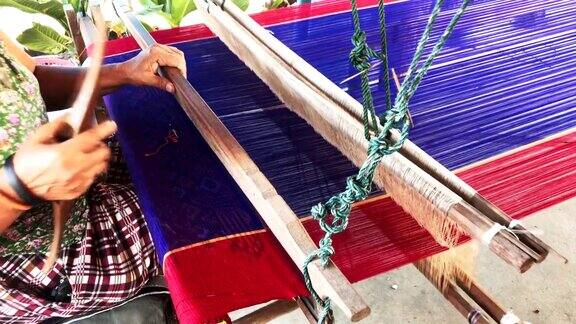 传统的泰国纺织业在手工艺村老妇人在木制织布机上工作纺纱制造棉织物