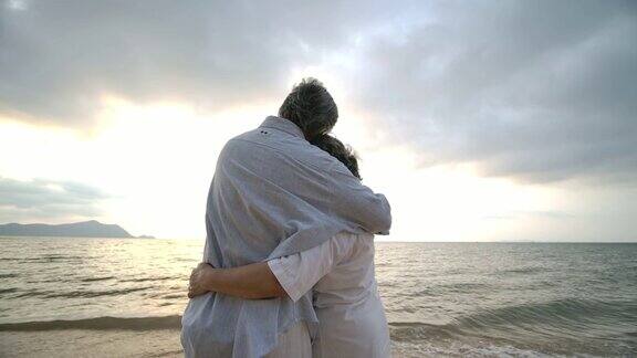 亚洲老年夫妇在海滩上拥抱对方的慢镜头