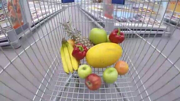 装着新鲜蔬菜和水果的购物车在超市里穿梭