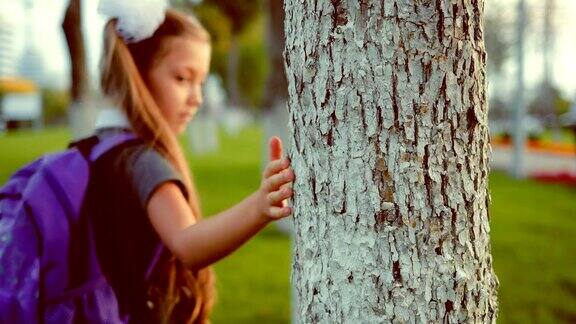 一个小女生走过一棵树用手掌碰了碰它