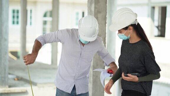 建筑师和工头戴着防护口罩在施工现场讨论文书工作承包商工人与业主一起检查夫妇检查新房建设