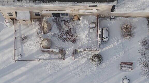 一个成年男子在一场冬季降雪后用铲子清理门廊上的积雪鸟瞰图正上方无人机视频