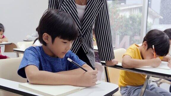 小男孩在教室里写书老师在辅导